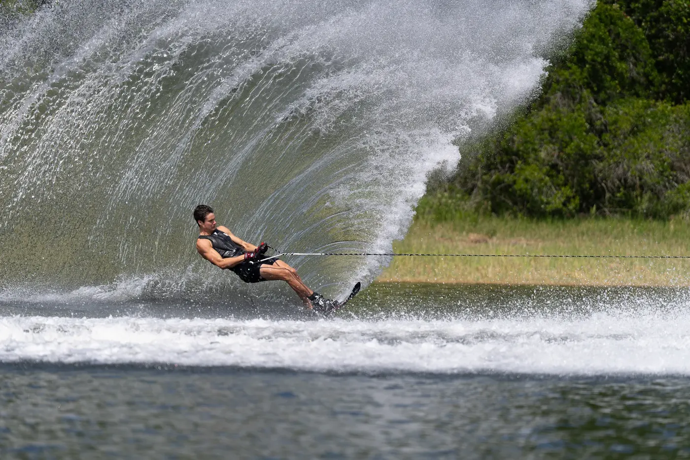 A skier carving a wall of spray behind a Nautique